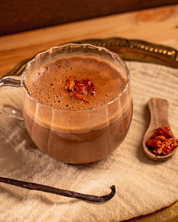 Gewürz Kakao mit Chili in einer Glastasse mit einer Vanilleschote als Dekoration! | © SONNENTOR